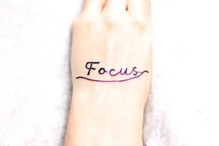Make me a minimal wrist tattoo with just word "Focus". Focus written horizontally on wrist symbolizing focus. tattoo design idea