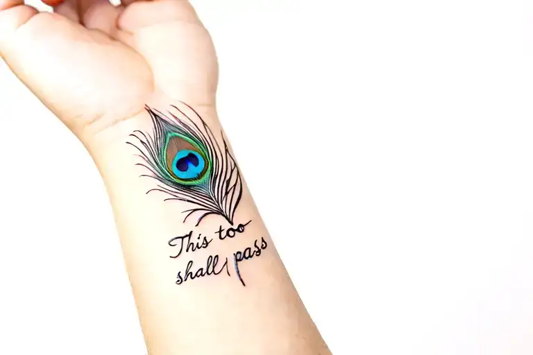"This too shall pass" on wrist with minimal peacock feather tattoo design idea