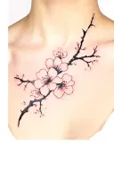 A fine-line, realistic cherry blossom tattoo placed centrally between the collarbones. The blossom has delicate black in tattoo design idea